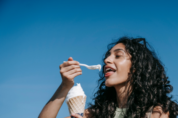 A woman enjoying a spoonful of ice cream, a delicious, safe, and soft food to enjoy after root canal therapy